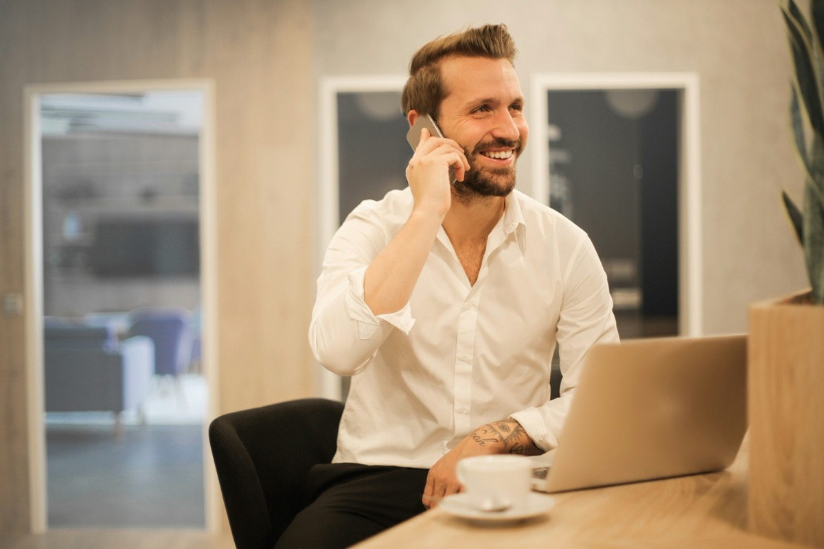 Lachende ondernemer aan de telefoon achter laptop